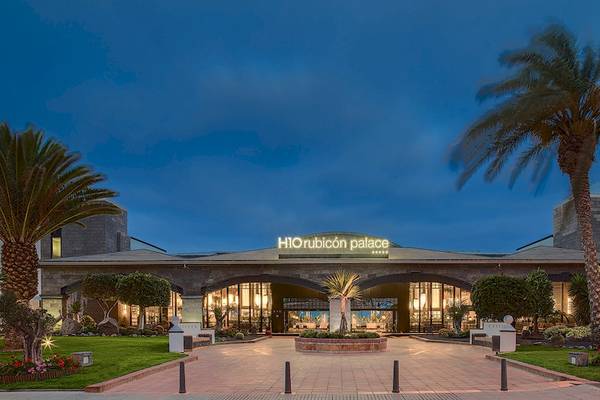 Außenansicht des H10 Rubicon Palace Hotels bei Nacht mit Beleuchtung und Palmen