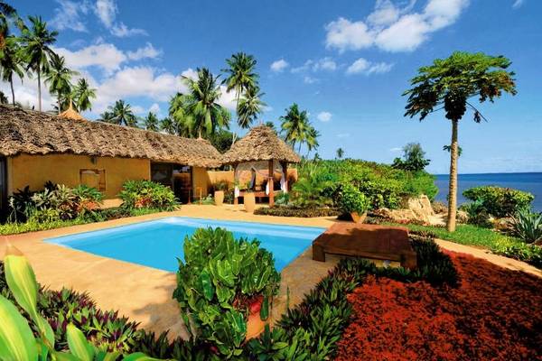Außenbereich des Zanzi Resorts mit Swimmingpool, Pflanzen und Palmen am Meer