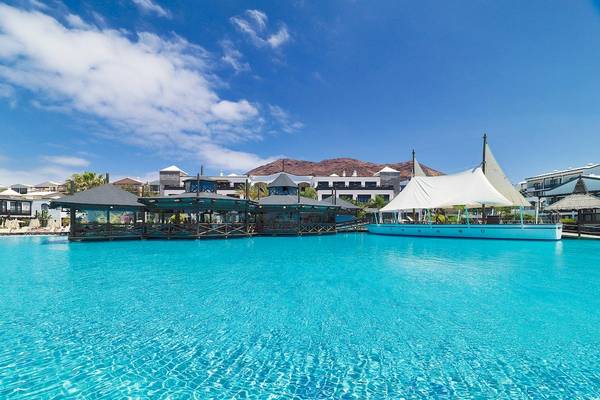 Das H10 Rubicon Palace Hotel mit einer blauen Poollandschaft im Hintergrund.