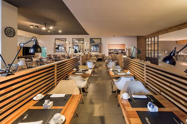 Innenansicht des Restaurants im H10 Rubicon Palace Hotel mit modernen Holztischen und Stühlen.