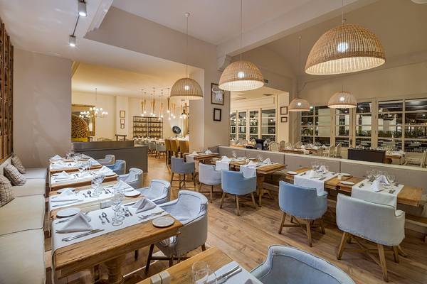 Innenraum des H10 Rubicon Palace Restaurants mit blauen Stühlen und Holztischen.