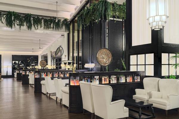 Innenansicht des H10 Rubicon Palace Hotels, Loungebereich mit weißen Sesseln, Bücherwand und schwarzem Tisch.