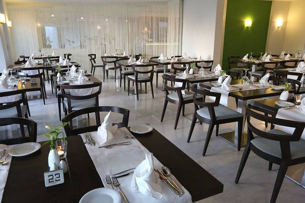 Innenansicht des Restaurants im Minos Mare Royal Hotel mit gedeckten Tischen und Stühlen.