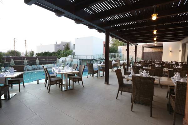 Außenbereich des Minos Mare Royal Hotels mit einem Swimmingpool und einem Restaurant.
