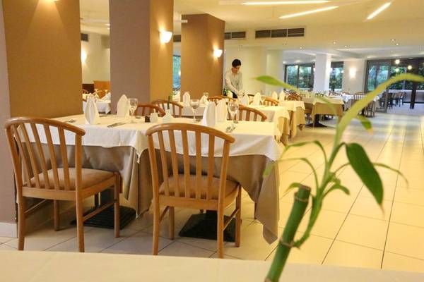 Restaurant im Minos Mare Royal Hotel mit gedeckten Tischen und einer Bedienung im Hintergrund.
