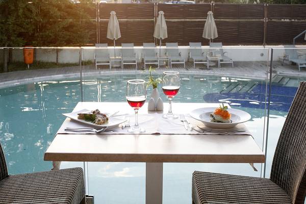 Ein Tisch am Pool mit Gläsern, Speisen und Getränken bei Sonnenuntergang.