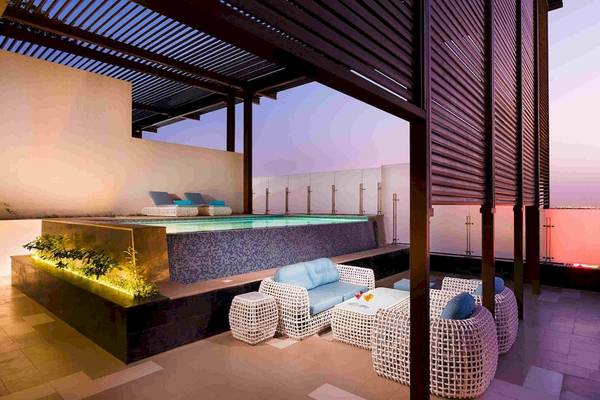 Terrasse des Grand Millennium Muscat Hotels mit Swimmingpool und Loungemöbeln