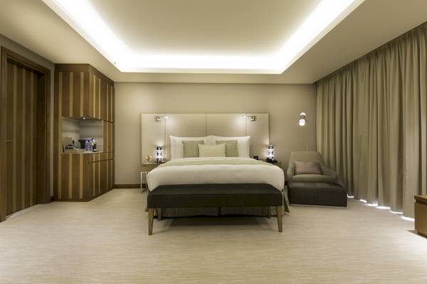 Schlafzimmer im Grand Millennium Muscat Hotel mit Doppelbett, Nachttischen und Beleuchtung.