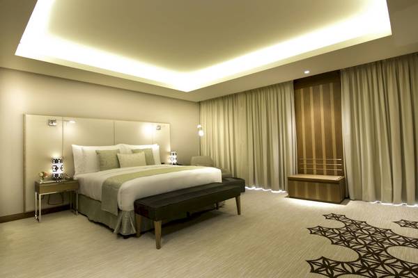 Schlafzimmer im Grand Millennium Muscat mit großem Bett, Nachttischen und luxuriöser Einrichtung.