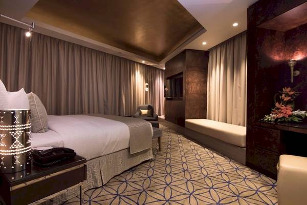Schlafzimmer im Grand Millennium Muscat Hotel mit Bett, Sitzecke und Dekor