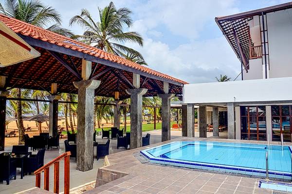 Pool-Terrasse des Goldi Sands Hotels mit blauem Wasser und umgeben von Palmen.