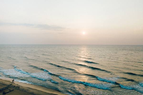 Strand mit Sonnenuntergang und Wellen, die zur Küste rollen