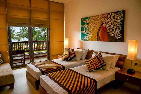 Zwei Betten im Zimmer im Goldi Sands Hotel mit Meerblick durch Glastüren.