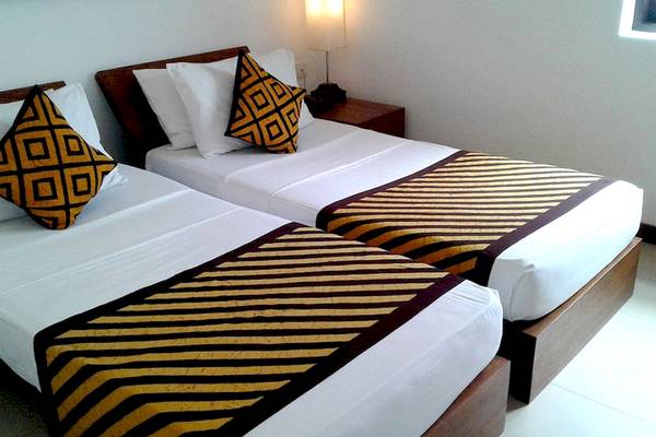 Zwei Betten im Goldi Sands Hotel mit farbigen Kissen und gestreiften Decken.