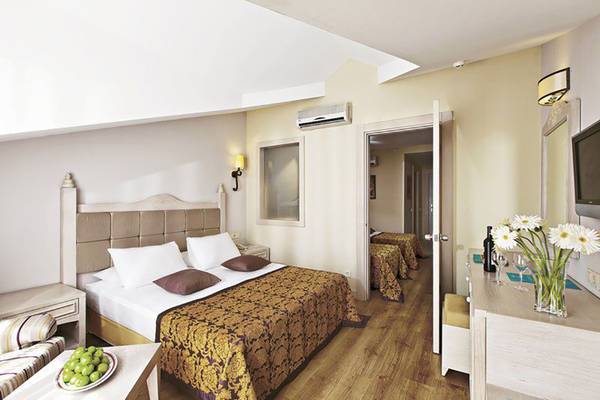 Schlafzimmer im Adalya Bliss Hotel mit einem Doppelbett, zwei Nachttischen, einer Couch und einer Kommode.