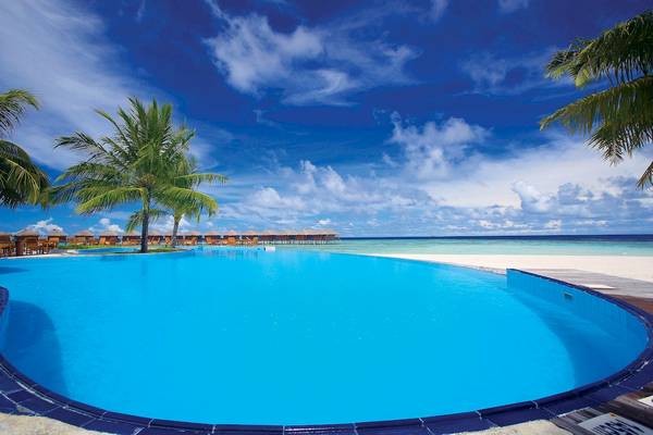 Strand und Pool im Filitheyo Island Resort mit blauem Himmel und Palmen