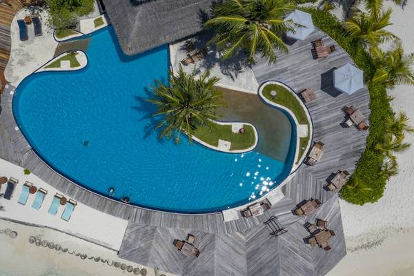 Oberflächenansicht des Infinity-Pools im Filitheyo Island Resort mit Liegestühlen und Sonnenschirmen.