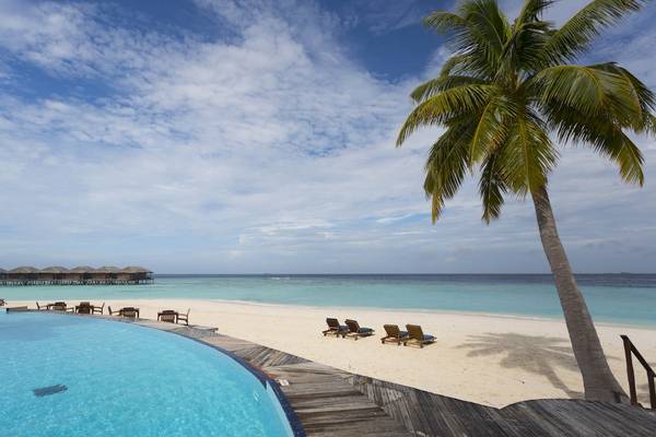 Strand mit Hotel und Pool am Filitheyo Island Resort mit blauem Himmel und weißen Wolken.