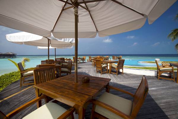 Holztische im Restaurant des Filitheyo Island Resorts mit Blick auf das Meer.