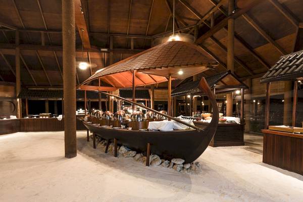 Innenbereich des Filitheyo Island Resorts mit einem großen Boot, das als Restaurant dient, und Steinen drumherum.