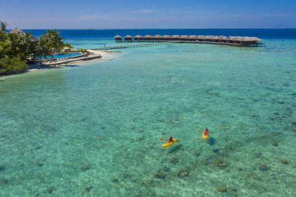 Außenansicht des Filitheyo Island Resorts mit zwei Personen in gelben Kajaks im Wasser.