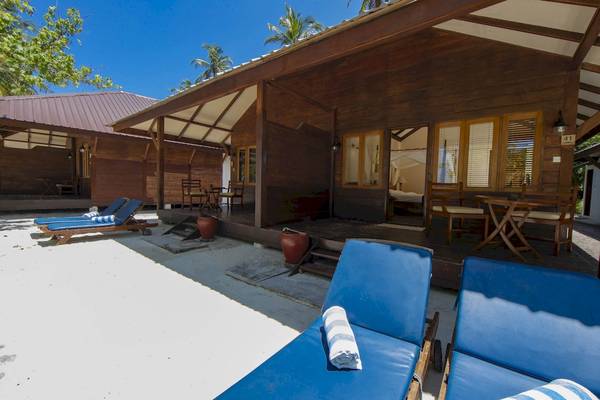 Holzbungalow mit Terrasse im Filitheyo Island Resort, umgeben von Palmen und Meer