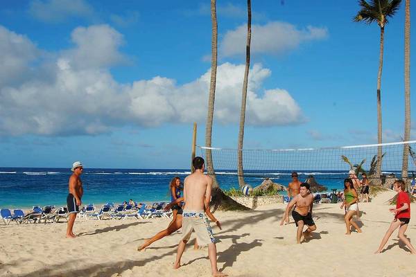 Mehrere Personen spielen Volleyball auf dem Strand des Occidental Caribe Hotels.
