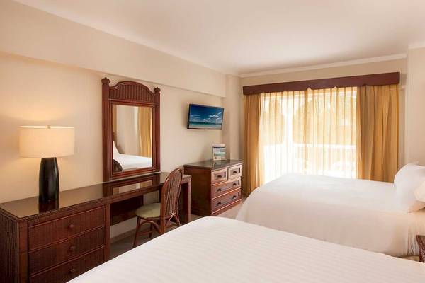 Doppelbettzimmer im Occidental Caribe Hotel mit Fernseher, Schreibtisch und Balkon.