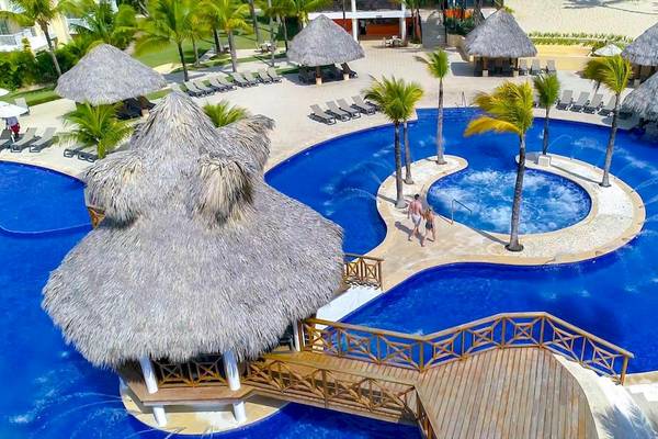 Luftaufnahme des Swimmingpools des Occidental Caribe Hotels mit Strohhütten und Sonnenliegen