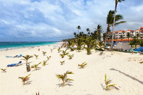 Strand mit weißen Palmen und einem Hotel im Hintergrund am Tag