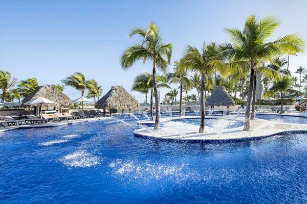 Poolbereich im Occidental Caribe Hotel mit Palmen, Sonnenliegen und Wasserfontänen.