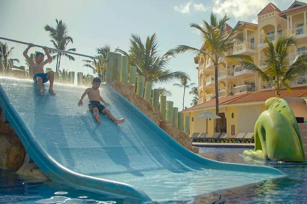 Zwei Kinder rutschen auf einer blauen Wasserrutsche im Schwimmbad des Occidental Caribe Hotels.
