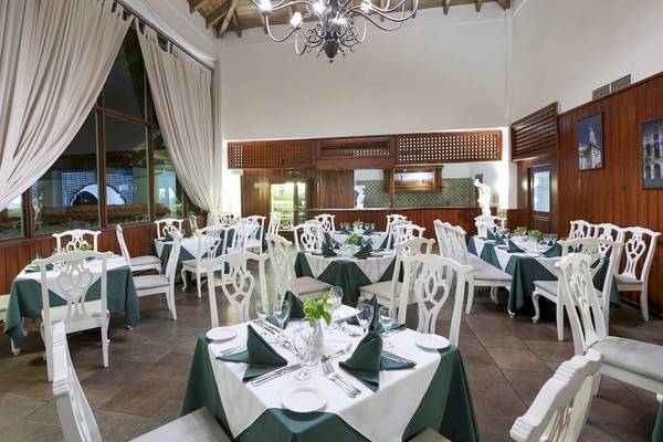 Innenbereich des Restaurants im Occidental Caribe Hotel mit grünen Tischdecken und weißen Stühlen.