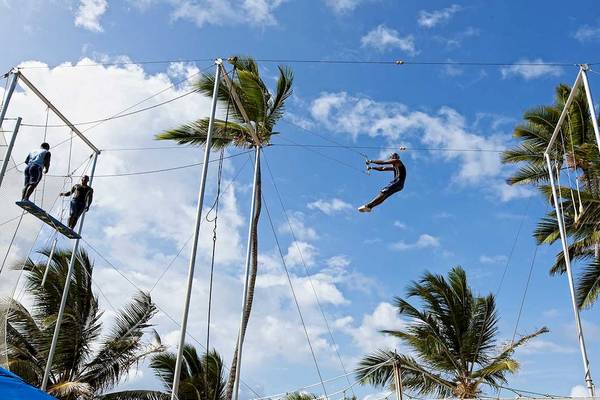 Trapezartisten im Freien vor dem Occidental Caribe Hotel, einer Person, die gerade vom Trapez springt.