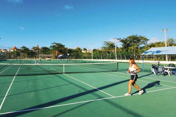 Tennisplatz mit einer Frau, die einen Schläger hält, im Freien beim Occidental Caribe Hotel.