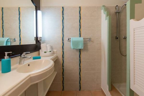Badezimmer im Pierre & Vacances Village Club Sainte-Anne mit Waschbecken, Spiegel und Dusche.