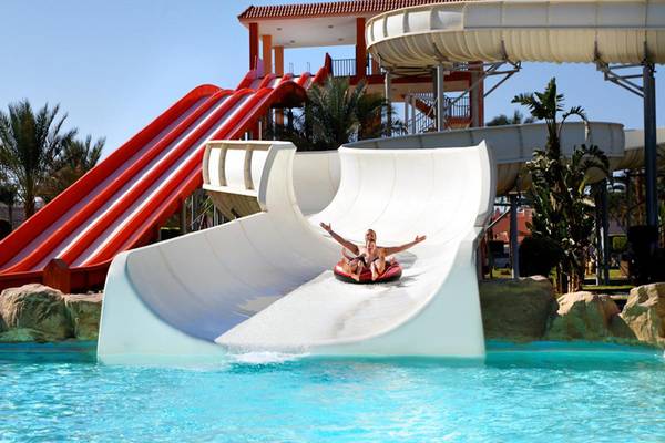 Zwei Personen rutschen auf einer roten Matte eine weisse Wasserrutsche im Beach Albatros Resort hinunter.