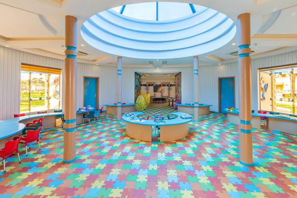 Kinderzimmer im Beach Albatros Resort mit bunten Puzzle-Boden, Tischen und Stühlen.
