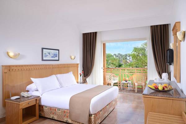 Ein Zimmer im Beach Albatros Resort mit einem Bett, einem Balkon und einem Ausblick auf eine Gartenlandschaft.