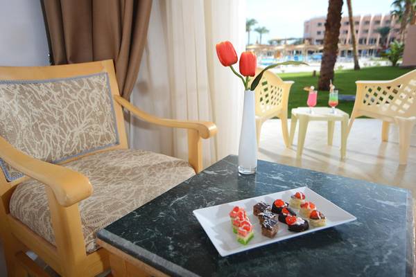 Ein Stuhl mit Tisch und Blumenvase mit Hotel im Hintergrund.