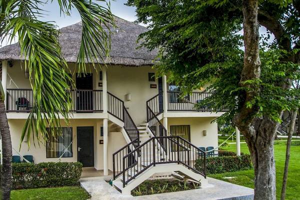 Außenansicht des Allegro Playacar Hotels mit zwei Stockwerken, Strohdach und grüner Umgebung.