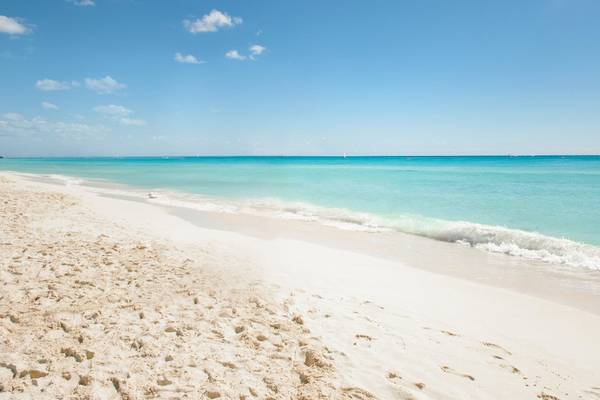 Strand neben dem Allegro Playacar Hotel mit blauem Himmel und weißen Wellen.