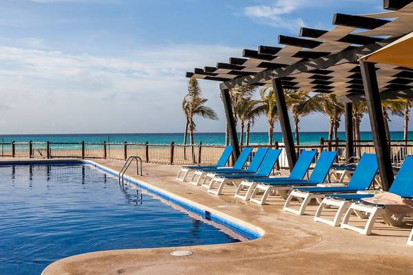 Am Hotel Allegro Playacar gibt es einen Pool mit blauen Liegestühlen und einer Pergola am Strand.