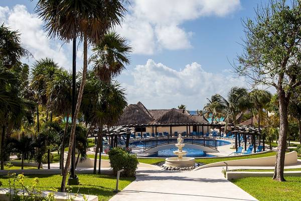 Außenbereich des Allegro Playacar Hotels mit Swimmingpool, Sonnenliegen und tropischen Bäumen.