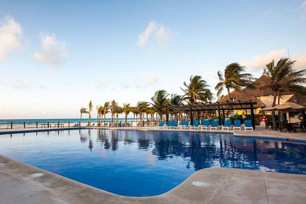 Außenpool des Allegro Playacar Hotels mit blauem Wasser, umgeben von Palmen und Sonnenliegen.