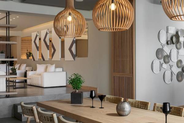 Inneneinrichtung der Ikones Seafront Luxury Suites mit hellem Dekor, großen Holzlampen und einer weißen Couch.
