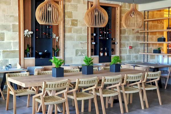 Innenbereich des Ikones Seafront Luxury Suites mit Holztischen, Stühlen und Pflanzen.