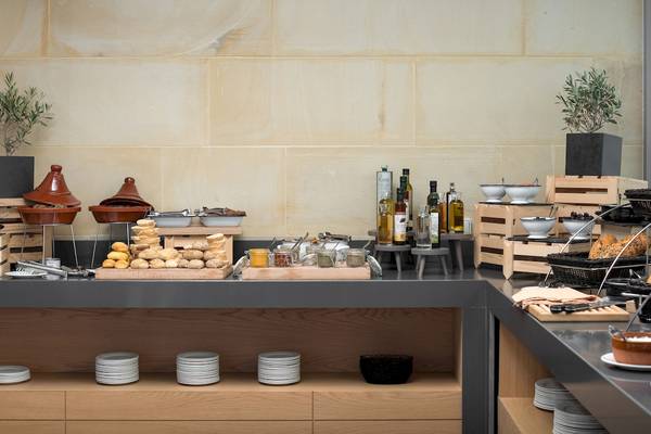 Frühstücksbuffet im Ikones Seafront Luxury Suites Hotel mit verschiedenen Broten, Oliven, Ölen und Gläsern.