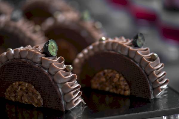 Nahaufnahme von Schokoladenkuchen der Ikones Seafront Luxury Suites mit gehackten Walnüssen und grüner Marzipan-Dekoration.