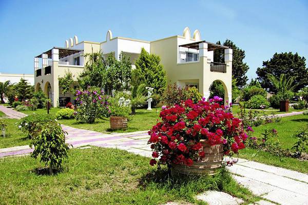 Außenansicht des Gaia Royal Hotels mit gepflegtem Garten und roten Blumen.